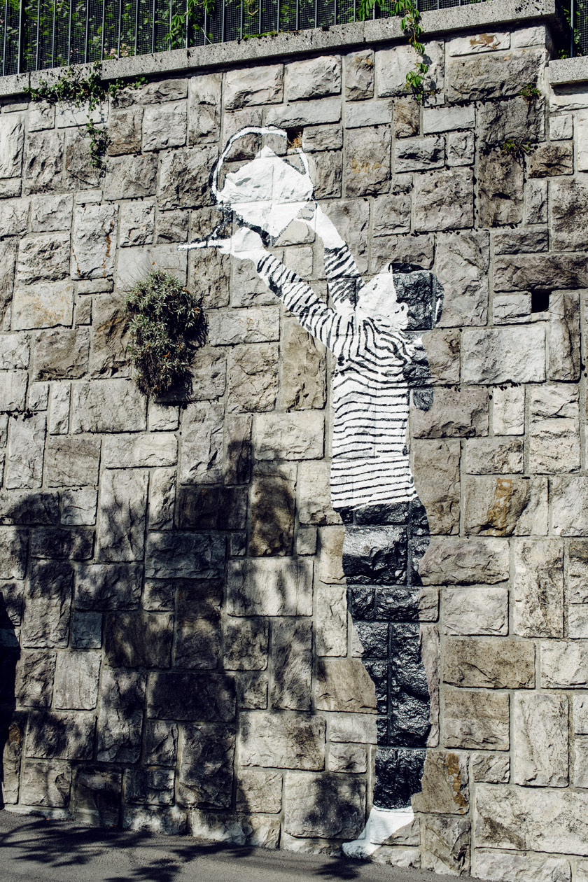 Lausanne Jardins 2019 – Place to Live – Un enfant peint sur les murs de Lausanne prend soin des plantes qui poussent de manière autonomes entre les pierres