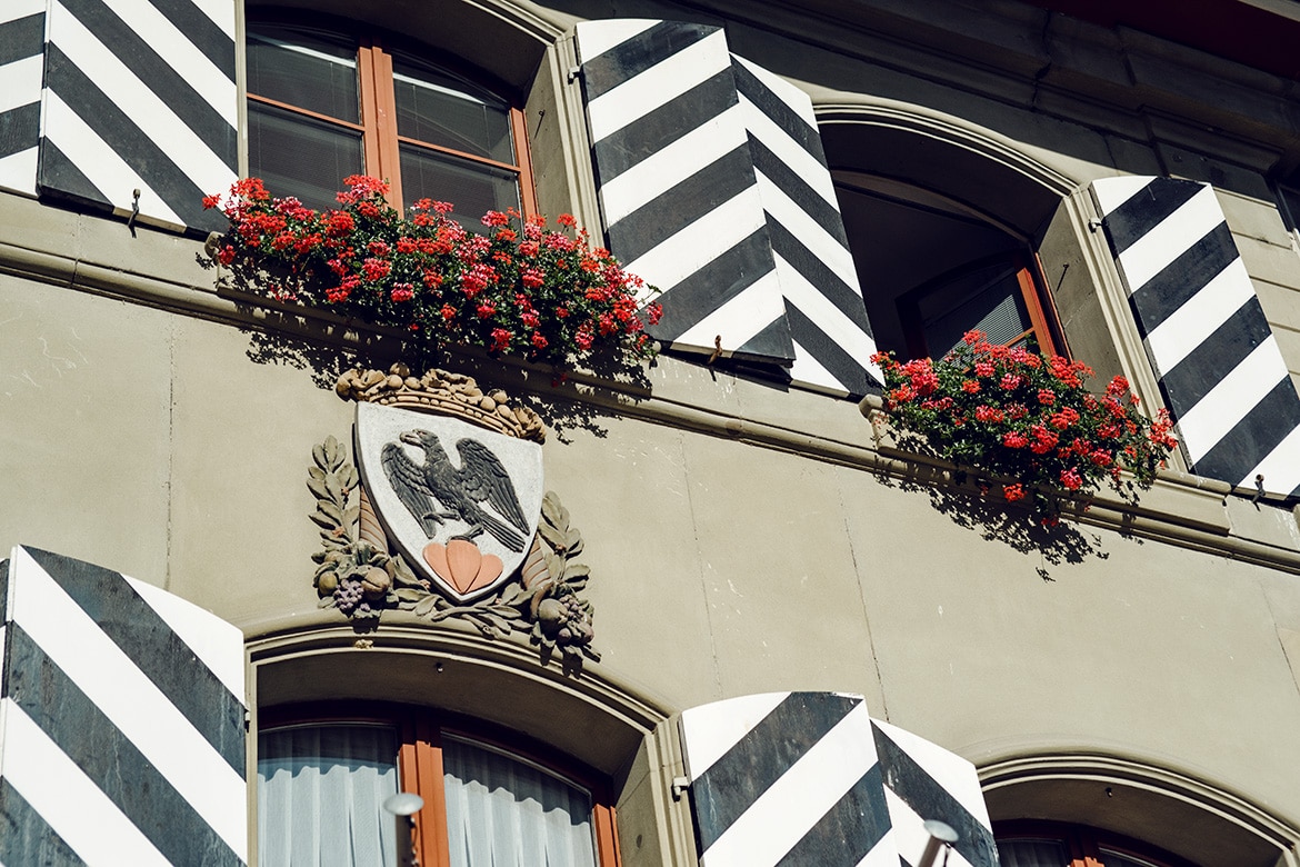 Façade de l'Hôtel de Ville d'Aarberg, avec le blason de la commune et des géraniums rouges aux fenêtres